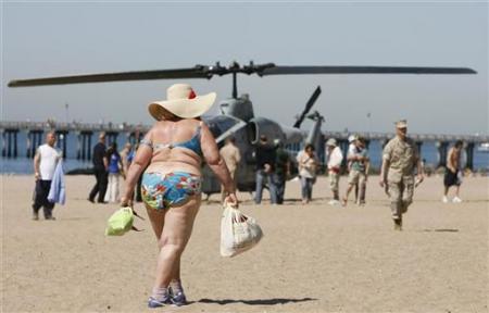 A woman walks on the beach at Coney Island past an AH-1 Cobra helicopter in New York May 21, 2009